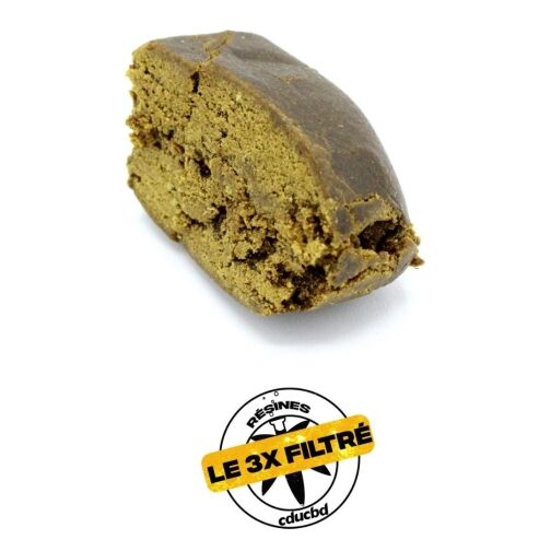 Un morceau de résine brune, légèrement effrité, avec une étiquette « Le 3x Filtré ».