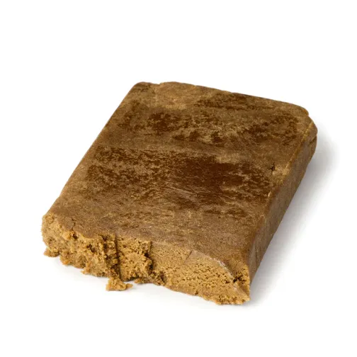 Bloc de résine brune compacte avec une surface légèrement brillante et une texture friable sur les bords.