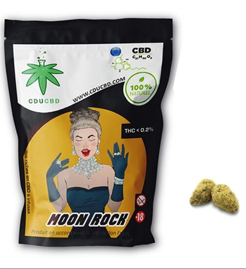 Sachet noir et doré de Moon Rock CBD avec illustration vintage et deux têtes de fleurs CBD enrobées de résine posées à côté.