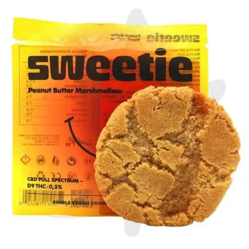 Un cookie doré et craquelé devant un sachet jaune et orange portant l'inscription "Sweetie".