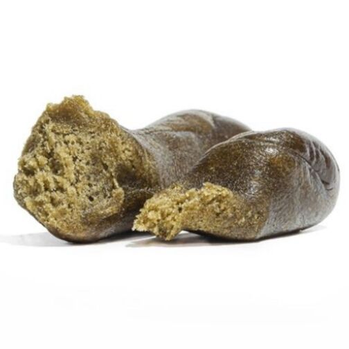 Un gros plan sur un morceau de haschisch brun, coupé en deux, révélant une texture moelleuse et friable à l'intérieur.