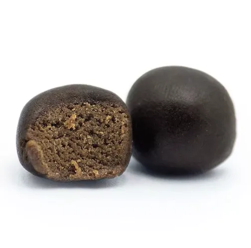 Deux boules de résine noire, l'une entière et l'autre coupée en deux, révélant une texture intérieure poreuse et brune.
