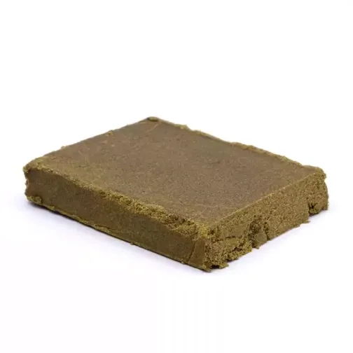 Morceau de résine de cannabis compact, couleur marron clair, à texture légèrement friable.