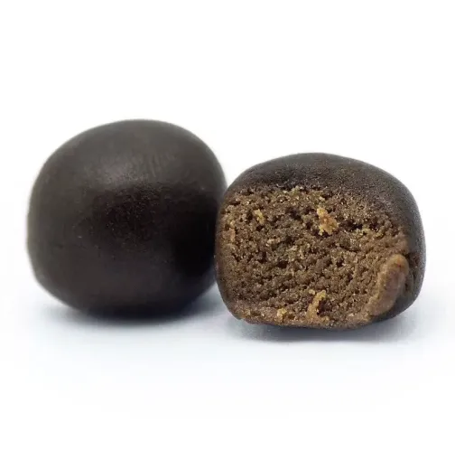Deux boules de résine noire, l'une entière, l'autre coupée révélant une texture intérieure brun clair.